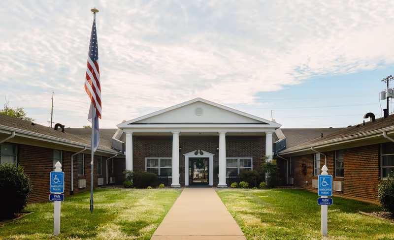 Front view of a brick senior living facility with a columned entrance.