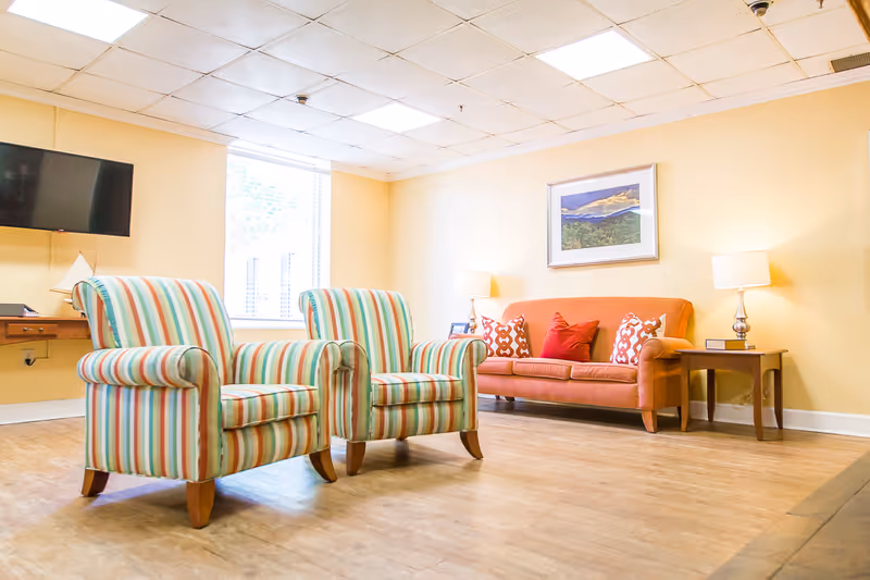 Colorful seating area with striped chairs and an orange sofa in a bright common lounge.