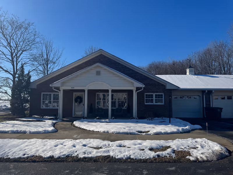 Snowy single-story brick facility with a covered front porch and rocking chairs