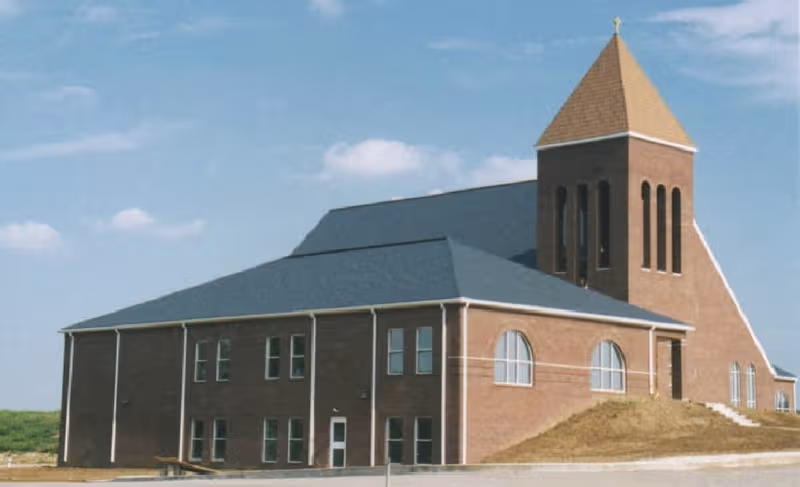 Exterior view of a brick facility with a tall tower and sloped roof.