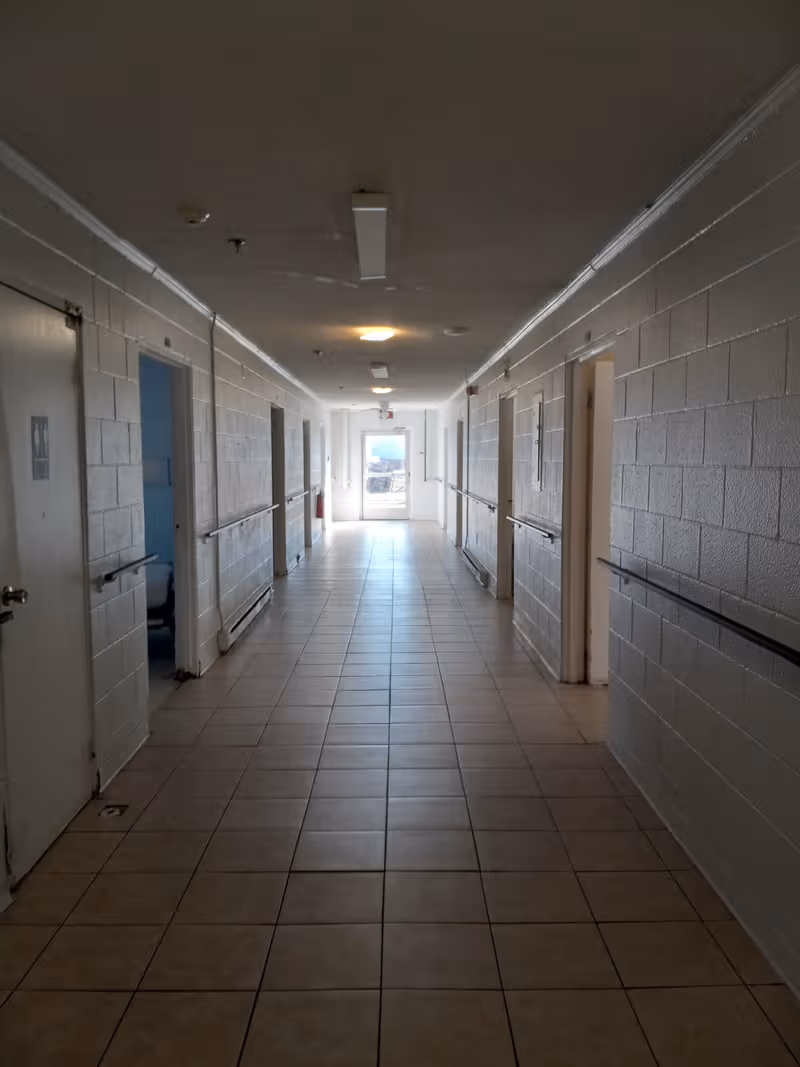 Long hallway in a senior living facility with doors along both sides.