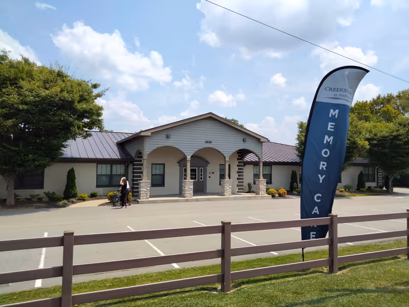 Exterior view of CreekSide on Bardstown memory care facility with front entry and banner