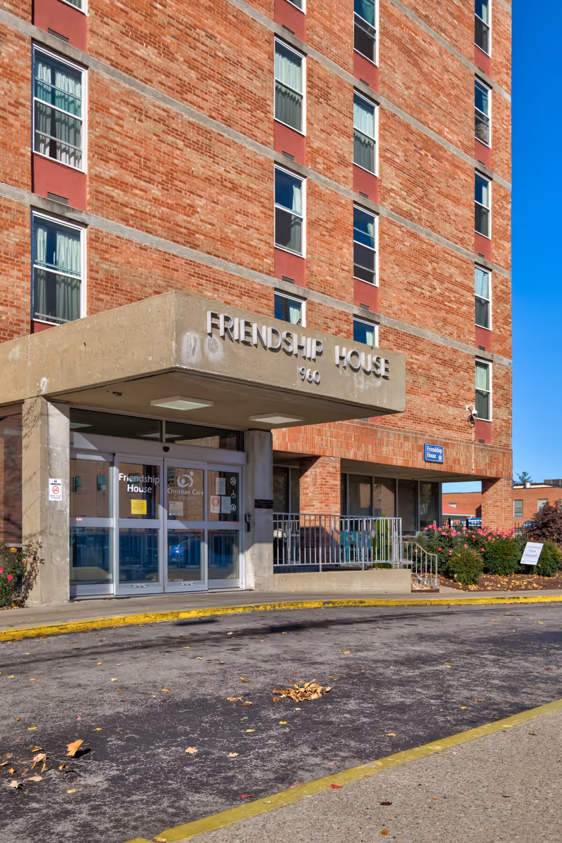 Entrance and facade of a multi-story brick building with a canopy sign reading "Friendship House".
