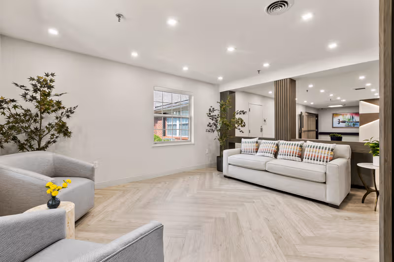 A bright lounge area with beige couches, potted plants, and modern decor.