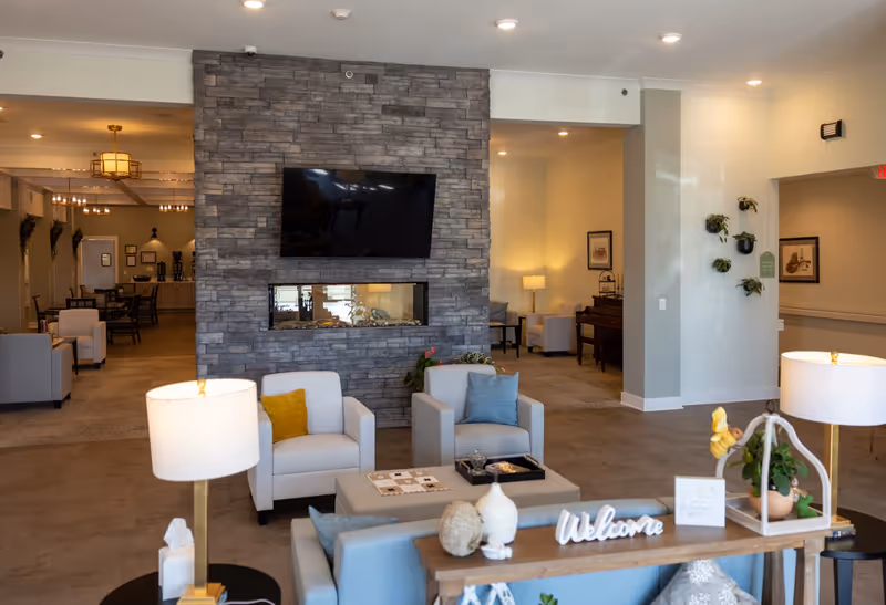 Spacious lobby lounge in a senior living facility with stone fireplace and seating.