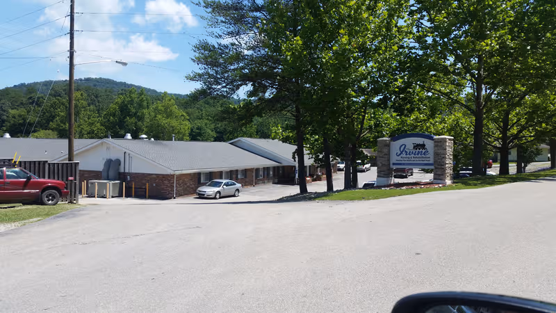 Exterior view of Irvine Nursing & Rehabilitation with front sign and parked cars.