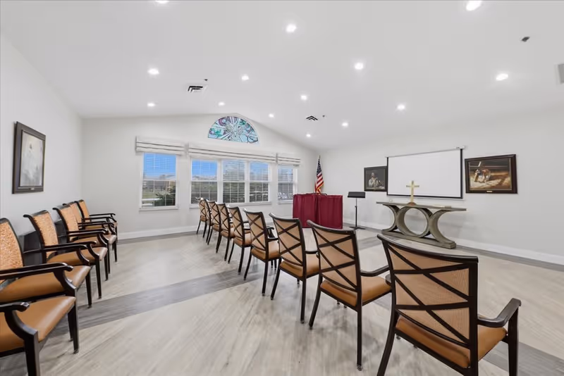 Chapel-style meeting room with chairs arranged toward an altar and cross.