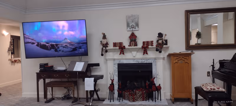 Living room interior with TV, fireplace, piano, holiday decor, and a large mirror.