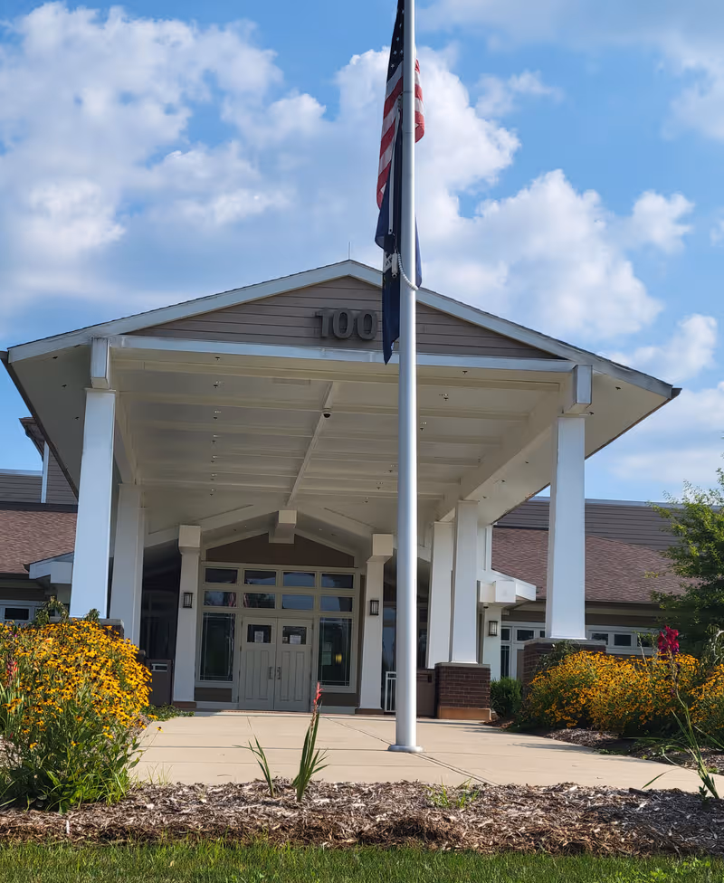 Front entrance of Radcliff Veterans Center with flagpole, covered walkway, and landscaped entry.