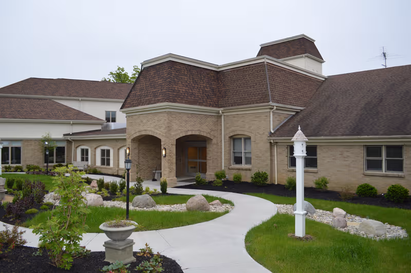 Exterior view of Carmel Manor senior living facility with brick architecture and landscaped grounds.