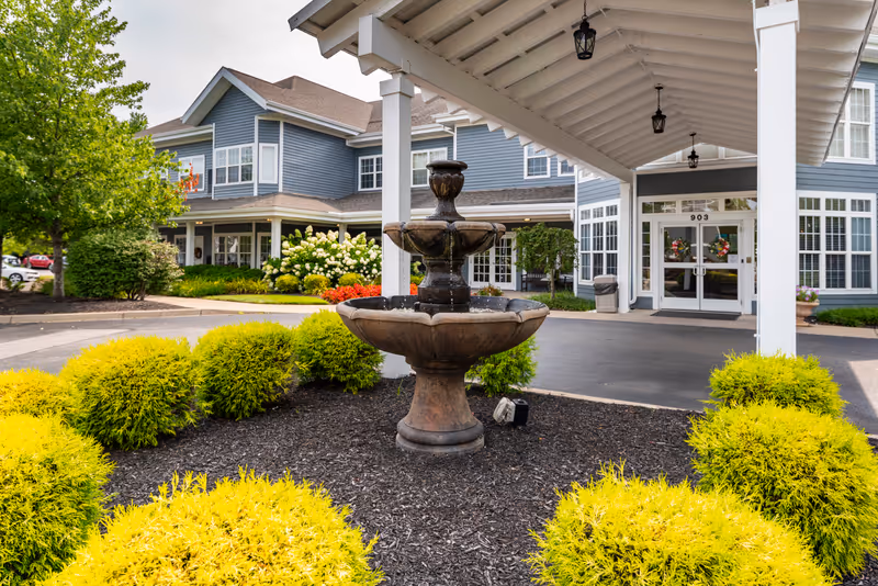 Front entrance of Arcadia Senior Living Louisville with a central fountain and shrubs.