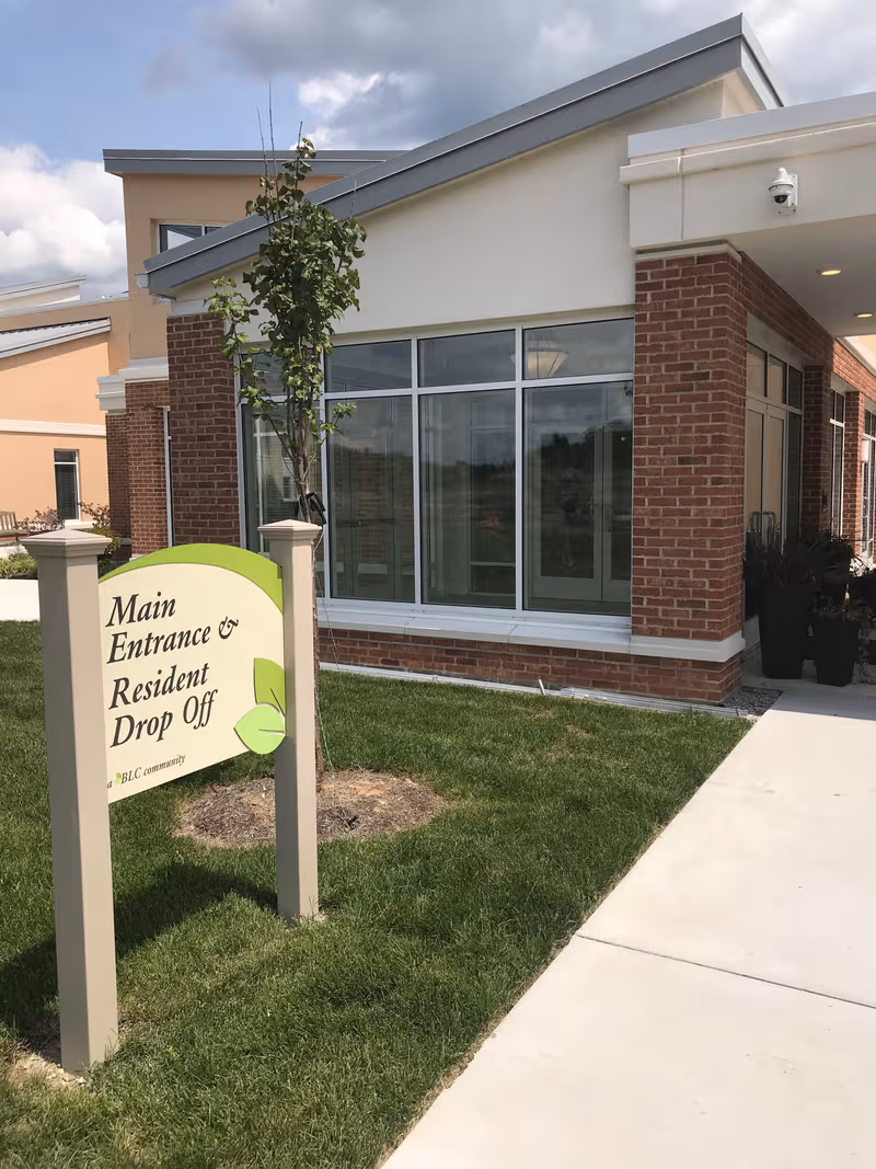 Exterior view of The Seasons at Alexandria facility with main entrance and drop-off sign.