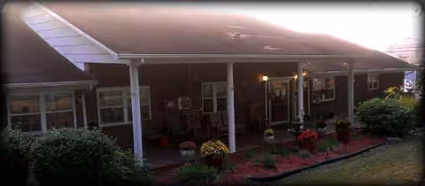 Front view of a brick senior living facility with a covered entry and flowering plants.
