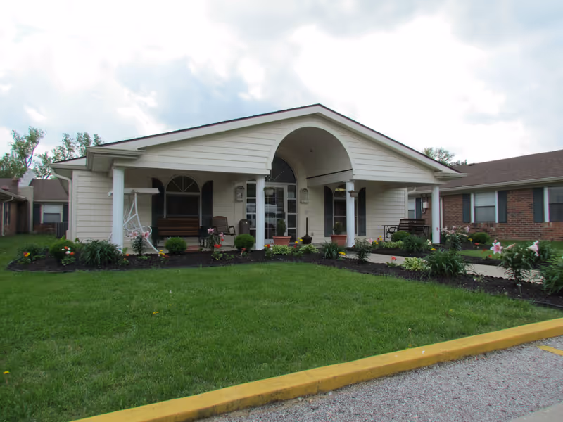 Front view of a single-story senior living facility with a covered porch and garden.