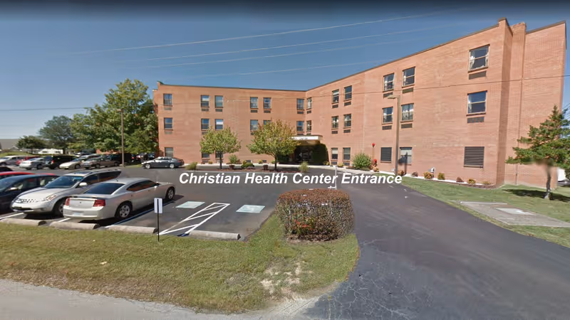 Exterior view of a brick health center building with parking and entrance labeled Christian Health Center.