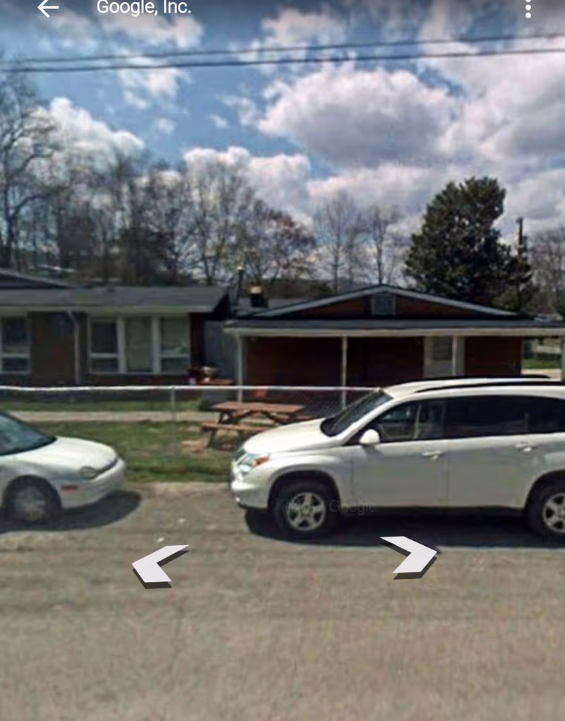 Exterior view of a single-story facility with a white SUV parked in front.
