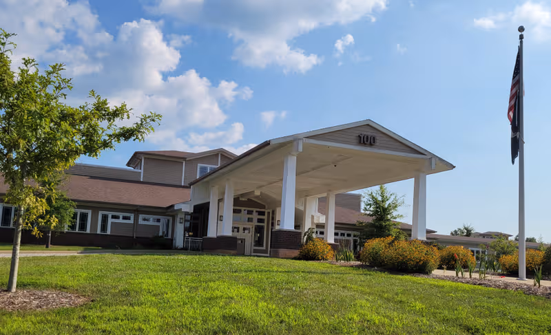 Front view of Radcliff Veterans Center with covered entrance, flagpole, and well-kept landscaping.
