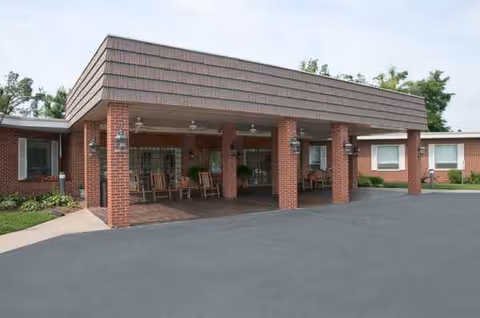 Brick senior living center entrance with a covered porch and seating.