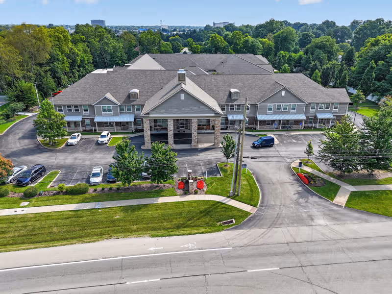 A large senior living facility from an aerial view with front entrance and parking.