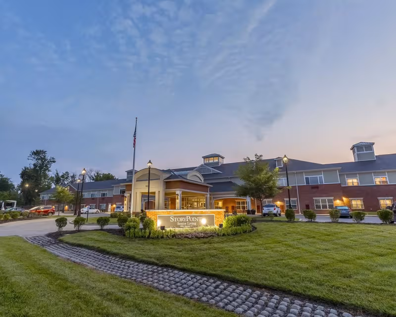 Exterior view of StoryPoint Prospect senior living facility with illuminated entrance sign and landscaping.