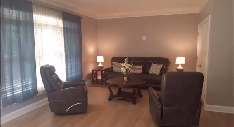 Cozy living room in Northfork Senior Living with leather sofas, coffee table, and lamps.