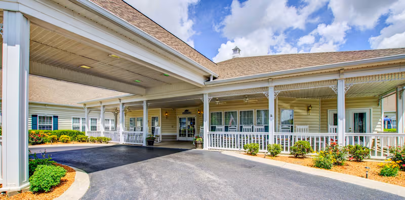 Senior living facility entrance with a covered front porch and shrubs.