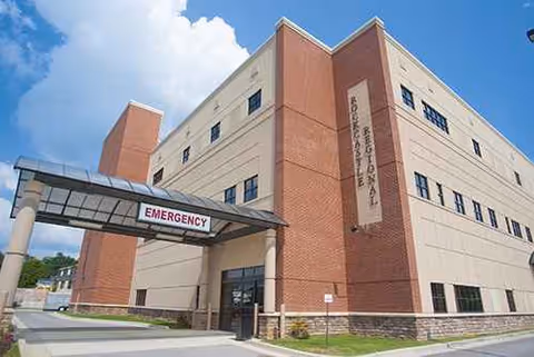 Exterior view of Rockcastle Regional Hospital and Respiratory Care with emergency entrance under a blue sky.