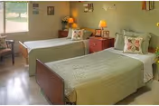 Two twin beds with green bedspreads and matching nightstands in a shared bedroom.