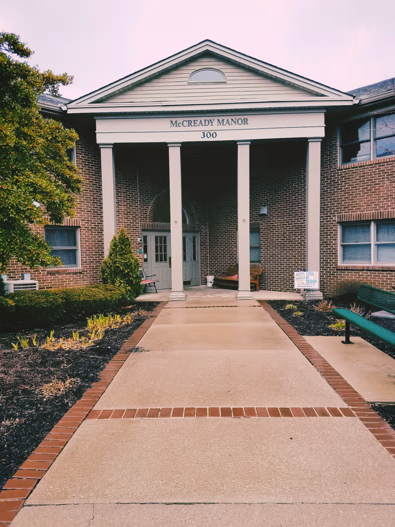 Front entrance of McCready Manor with brick facade, columns, and a wide walkway.