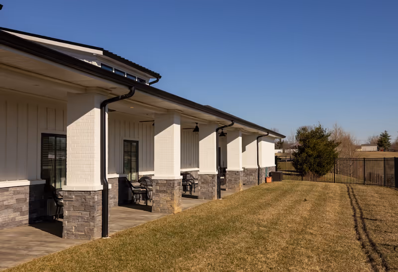 Exterior view of a single-story senior living facility with a porch and seating.