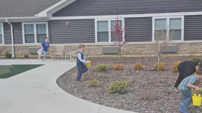 Outdoor view of Charter Senior Living of Paducah with people walking near the building and garden.