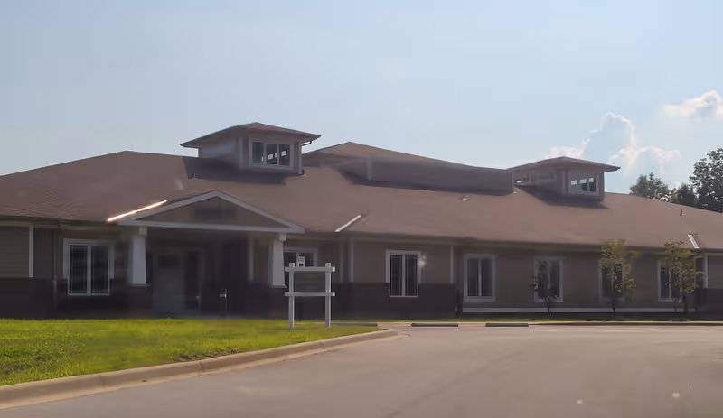 Exterior view of Radcliff Veterans Center building with driveway, lawn, and parking area.