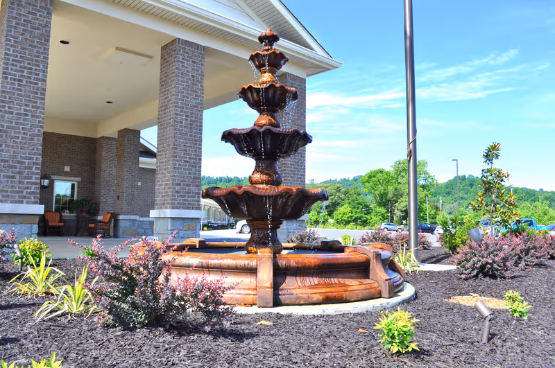 Front exterior of Barbourville Health and Rehabilitation Center with a multi-tier fountain and landscaped entrance.