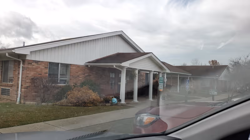Front exterior of a single-story brick senior care facility with a covered entrance.
