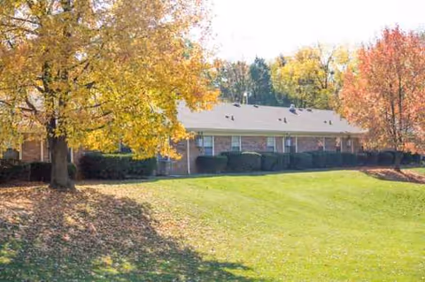 Autumn-colored trees frame a single-story brick senior living facility with a green lawn