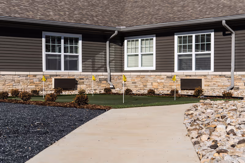 Exterior view of Charter Senior Living of Paducah with windows, stone facade, and landscaped shrubs.