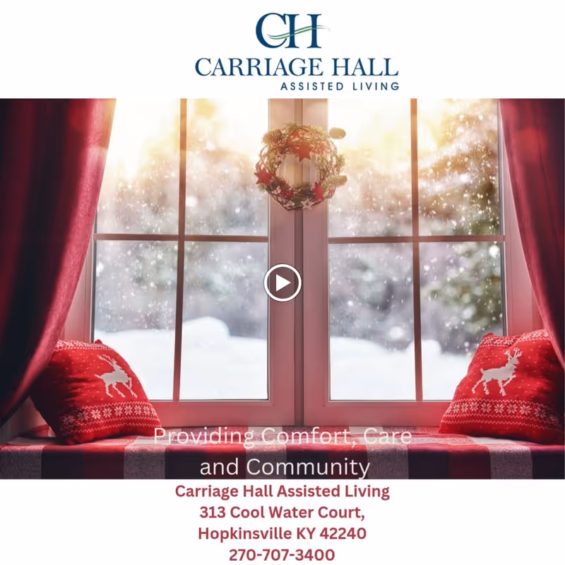 Window seat with red cushions featuring white reindeer patterns, a small holiday wreath hanging on the window, and a snowy winter scene outside. The image includes the Carriage Hall Assisted Living logo and contact information.