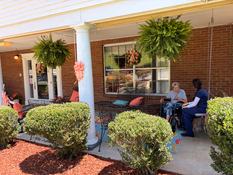 Outdoor porch at Breathitt Health & Rehabilitation with resident and caregiver chatting.