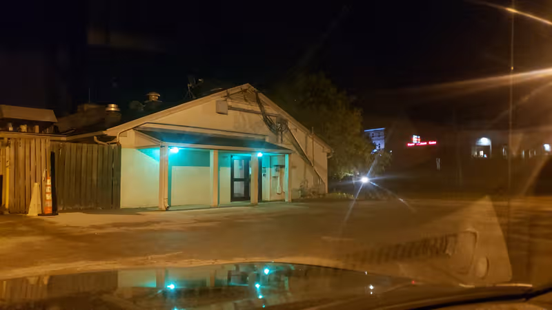Night exterior of Crestview Healthcare and Rehabilitation with teal illuminated entrance and fence.